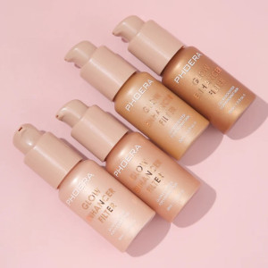 Four PHOERA Glow Enhancer Filter foundation bottles with pump dispensers arranged on a pink background, showcasing makeup products.