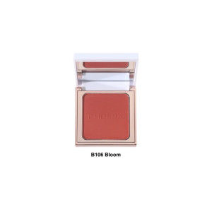 Compact blush in a gold-tone case, open to reveal coral-pink powder labeled 'B106 Bloom' with a mirrored lid nearby